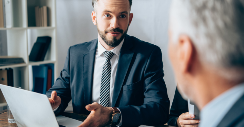 Businessman pointing at laptop near papers and investor