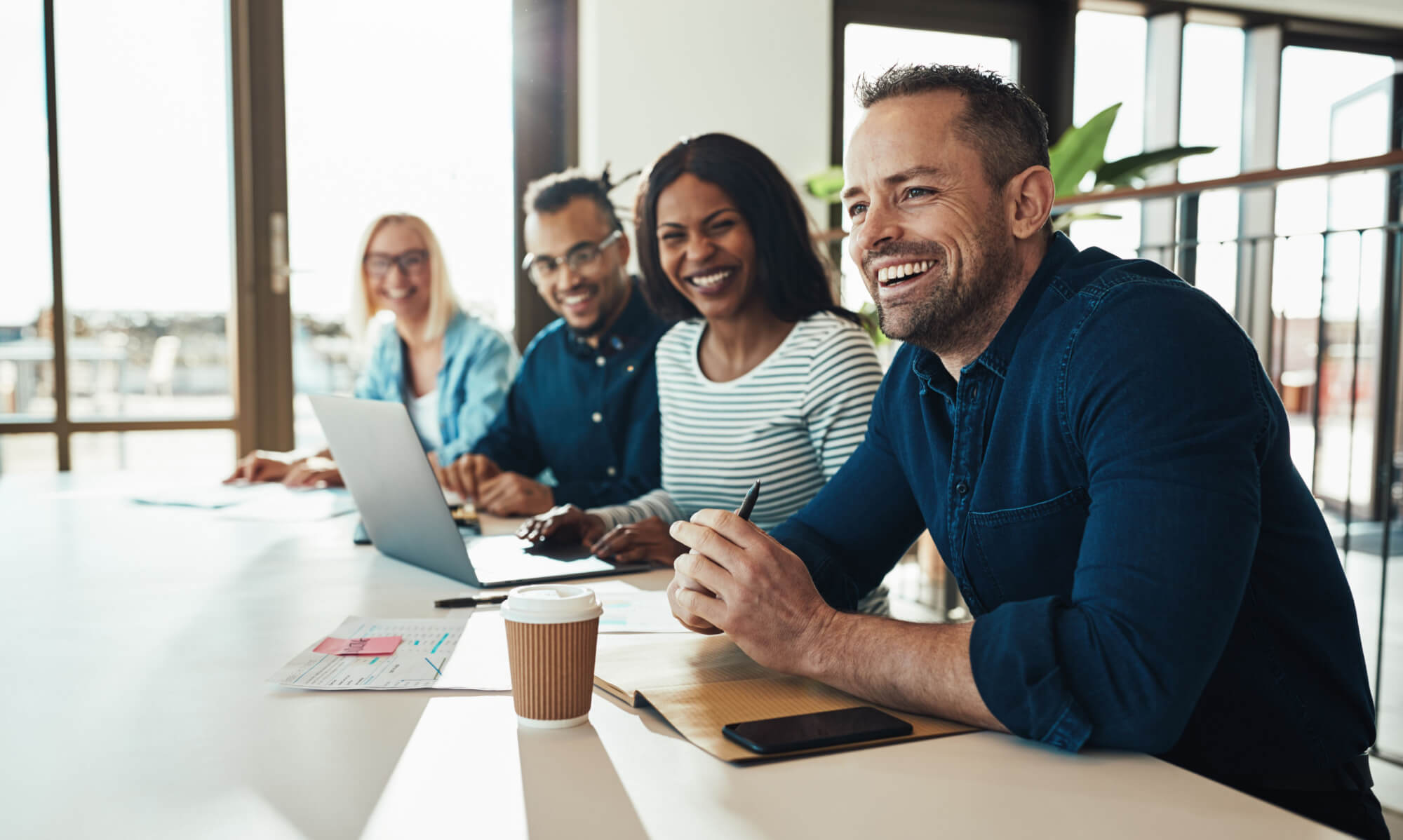 Men and women smiling and sitting at work