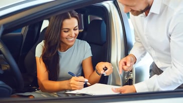 Woman sitting in a car signing to buy the car