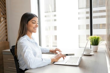 Woman sitting at desk with laptop reviewing her insurance audit information